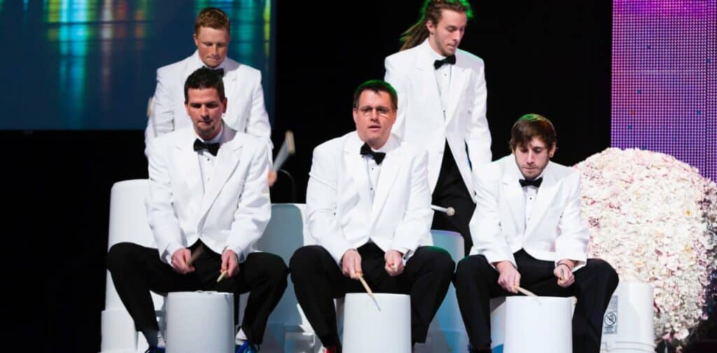 Circle City Bucket Drummers performing in tuxes on stage at an event