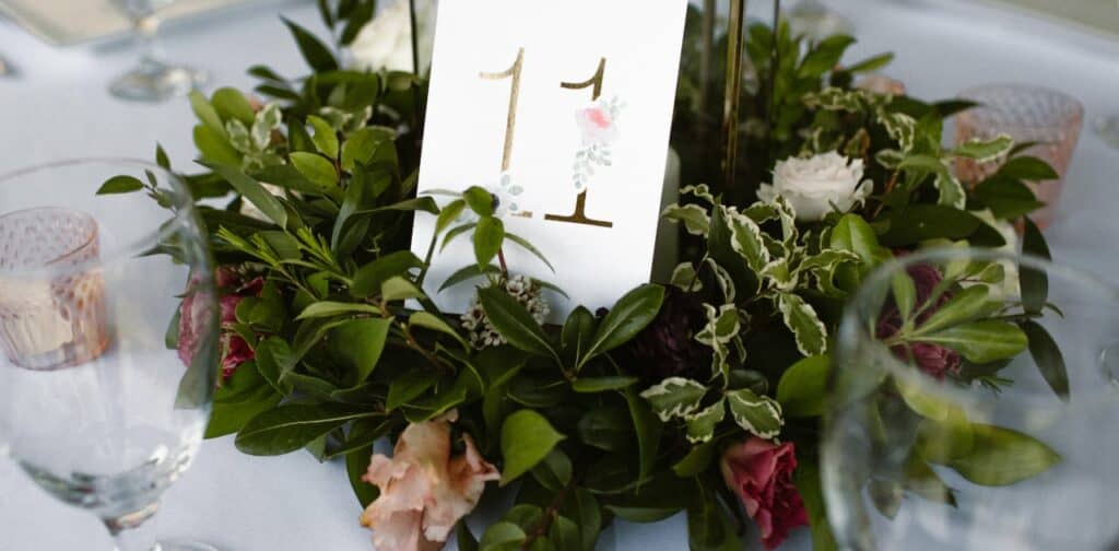 Photo of table centerpiece with a seat number surrounded by leave and flowers