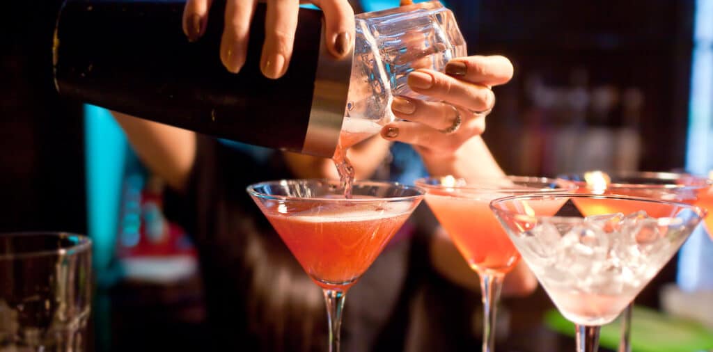 A bartender pouring a drink at a successful cocktail party