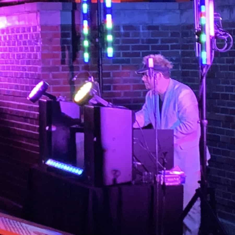 A technician stands near a wall controlling stage lights, audio equipment, and other event effects.