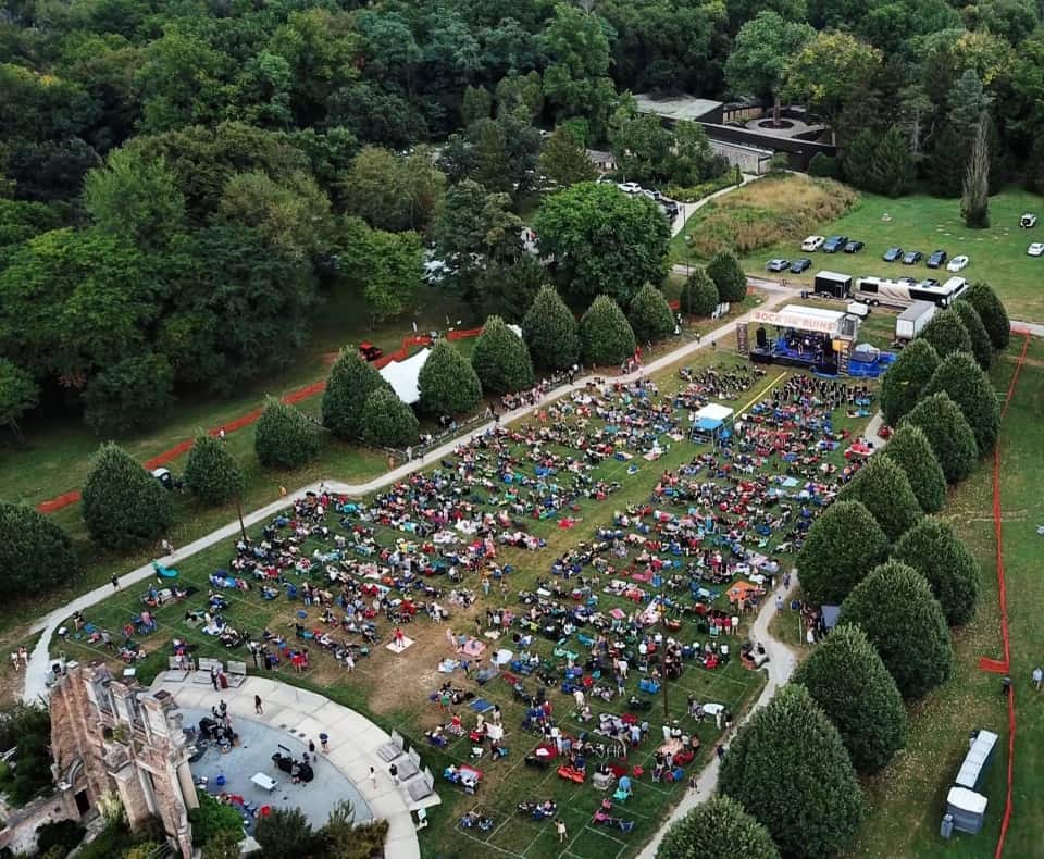 An aerial drone photo of a large outdoor music festival with hundreds of attendees and a stage