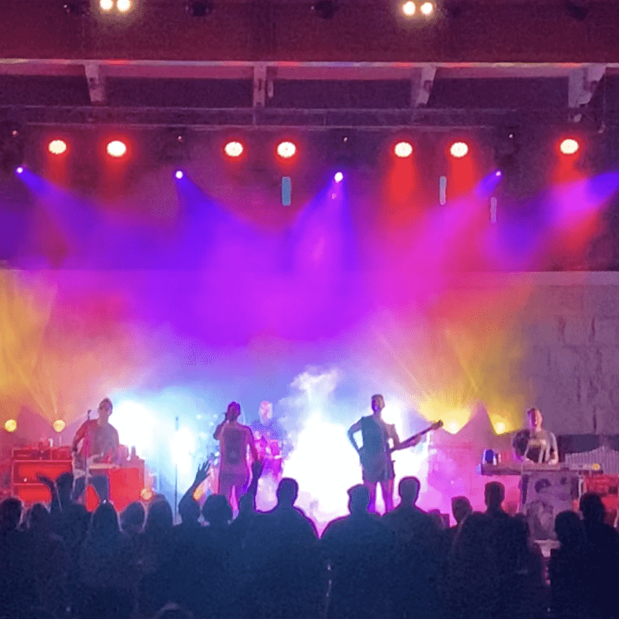 Four musicians in a rock concert under colorful stage lights