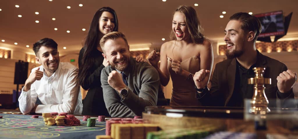 Happy people are betting in gambling at roulette poker in a casino.