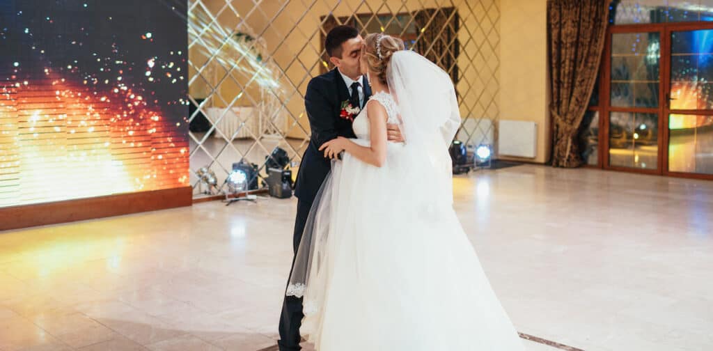 Bride and groom kiss in the middle of an empty dance floor